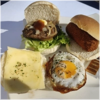 3 witte bolletjes brood met een rundvlees kroket, een gebakken ei en een hamburger